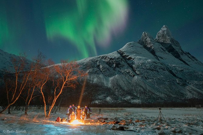 Green aurora over a fire burning on a frozen Arctic shore